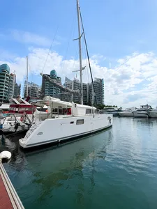Zen Sea catamaran moored in Singapore marina with sail rig and skyline towers, ready for a kayak, SUP and snorkel cruise