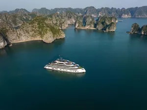 Aerial view of the Doris Cruise ship floating in Halong Bay’s calm waters beside towering limestone karsts on a 2D1N cruise