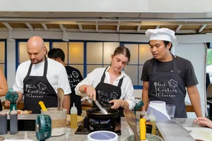Gili Islands cooking class in Lombok: instructors guide guests at a wok station, preparing Indonesian dishes and peanut sauce