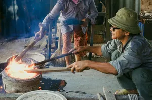 Local cook grilling at an open fire with sparks, served during a Hoi An secret waterfall motorbike adventure stop