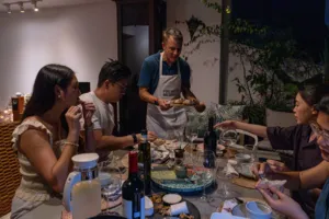 French Cooking Lab host guiding a group tasting French baguettes and sunset drinks in a cosy loft in Singapore — private dining Singapore