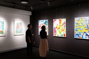 Visitors standing before framed paintings on gallery walls at Quang San Art Museum during a Vietnamese art tour in Ho Chi Minh City