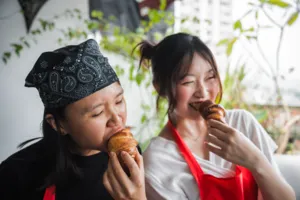 Two guests tasting flaky croissants at a French Cooking Lab bake-in-home session in Singapore courtyard dining