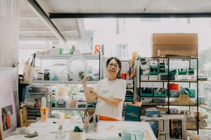 Tan Sock Fong holding a translucent glass centrepiece in the Art Glass Centre studio, Singapore—workshops in Singapore