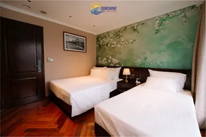 Sunshine Golden Cruises cabin bedroom on a Cat Ba cruise with two beds, warm lighting and a mural-style wall behind
