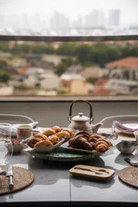 Croissants arranged on serving trays with tea set on a balcony table overlooking Singapore at a French Cooking Lab bake session