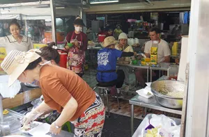 Local street-food stall where cooks plate bowls of noodles over large pots, showing everyday flavours on a Mekong Island bike excursion