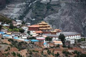 Terraced hillside village with multi-building Tibetan monastery complex and prayer halls in Shangri-La’s Meili region