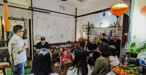 Seorang fasilitator menunjuk dinding bagan kelahiran sementara sekelompok kecil mendengarkan di workshop Chan Dat Living Room, Hoi An
