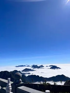 Balcony railing with white ornaments overlooking distant ridges and a sea of clouds at dawn during a 1-day eco trek, at Mt Fansipan
