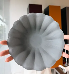 Hands holding a European-style ceramic plate form with a scalloped rim in a Singapore pottery studio