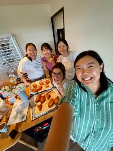 Smiling group posing at a kitchen table with trays of baked shio pan after flavoured butter making with The Daily Staples in Singapore