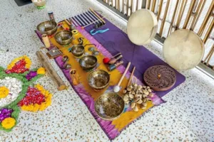 Assortment of brass singing bowls, chimes and mallets on a purple mat with flower petals, ready for sound healing in Canggu
