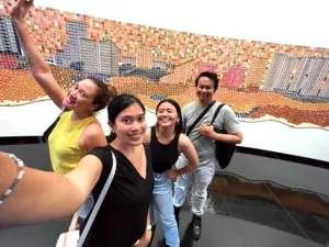 Friends pose on a rooftop terrace with a colourful tiled mural wall during a Singapore team challenge — team building Singapore