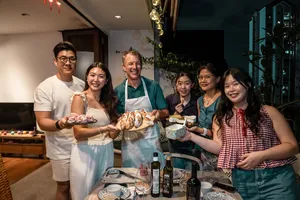 Small group in aprons celebrating French baguettes and drinks in a cosy loft private dining Singapore