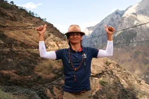 Trekker on the Lesser-Known high trail of Tiger Leaping Gorge in Lijiang, raising both arms beside a safety net