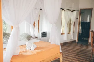 White-canopy bed in a bright guest room at Omunity Bali in Bali, part of a 3D2N sacred retreat