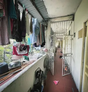Narrow hallway in Hanoi collective housing with barred doors, hanging laundry and shoes along the corridor.