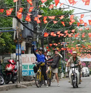 Cyclists riding along a festive street with red Vietnamese flags on Mekong Island near Ho Chi Minh City during a bike tour