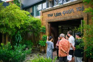 Group entering a Hanoi courtyard workshop through an arched doorway bordered by bamboo plants and lush greenery