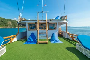 La Famille Komodo boat deck with green turf and blue beanbags, ocean view beyond the rail on a 3D2N trip in Labuan Bajo