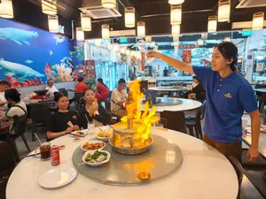 Diners around a round table watching a flame centerpiece at a Geylang-area Singapore restaurant during a private night walk