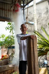 会安一处廊檐下,一位老人手拿竹卷,在参观过程中编织草席