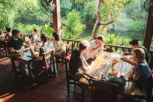 Guests eating together at a riverside dining deck at Khao Sok Riverside Cottages in Khao Sok National Park