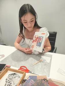 A participant places pieces on her vision board for gemstones in Singapore, with templates and tools on the table; workshops in Singapore