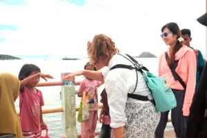 Tour group in life jackets leaning on a boat rail and waving while travelling across the water, Rinca day trip in Labuan Bajo