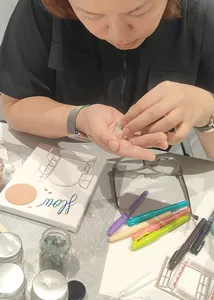 Close-up of hands assembling a vision board charm on a table of craft tools at Gemstory for birthday activities Singapore