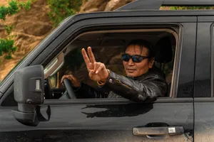 Tibetan guide in a tour car window giving a peace sign on the road to Shangri-La during the 6-day loop