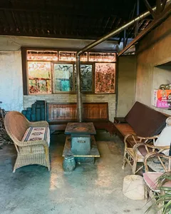 Guesthouse lounge in Lijiang with woven chairs, wooden tables, and a service counter by large windows, included in the stay