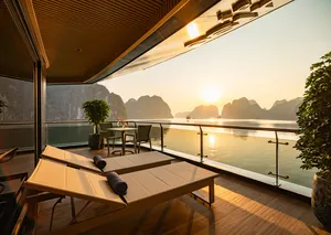 Private spa sun lounger on a Doris Cruise balcony overlooking Halong Bay at sunrise, with limestone karsts in the distance