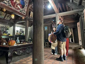 Backpackers standing in a traditional wooden home at Duong Lam ancient village near Hanoi during hands-on rice farming day