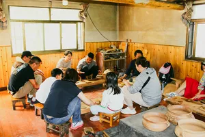 Pottery workshop in Shangri-La with a small group shaping clay at wooden tables, inside a warm community room