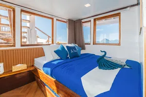 La Famille cabin on the Komodo boat with a blue bed, window views and a folded-towel swan, for 3D2N stays in Labuan Bajo