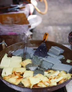 Smoky street-food wok in Lijiang with cubed foods sizzling over charcoal at a street stall during a local food hunt