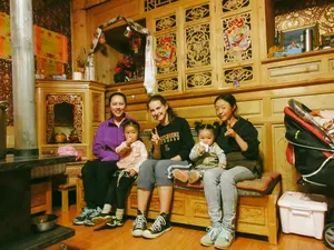 Family gathering indoors in a Tibetan homestay in Shangri-La, with two adults and two children smiling on a bench