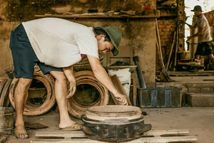 Man adjusting a metal cart in a roadside workshop during a Hoi An secret waterfall motorbike adventure route