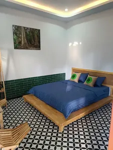 Quiet bedroom interior for a private 3D2N Cat Tien ethical tour, with a double bed and forest wall art by Next Continent