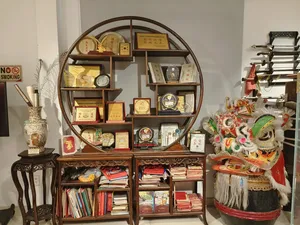 Ho Chi Minh City Chinatown lion-dance museum shelf showing awards, books and a decorated lion mask in a display case