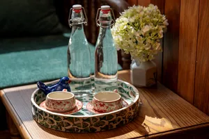 Tea and drinks set on a decorative tray with patterned cups and glass bottles, ready for a relaxing moment onboard Cat Ba Ocean Cruises