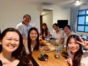 在新加坡的佛卡夏课程工作坊中,面带笑容的参与者围坐在木桌旁,桌上摆着杯子和面包