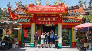 胡志明市一座中式庙宇入口,挂着红色喜庆横幅,庭院里游客挥手拍照