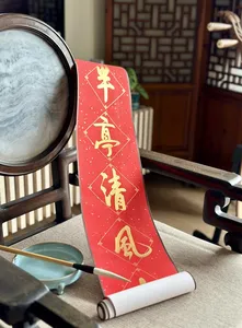 Red Chinese calligraphy strip on a desk with a brush, magnifying glass and rolled practice paper during calligraphy workshops in Singapore