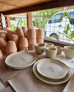 Unpainted ceramic bowls and plates with leaf motifs arranged on a studio table at Ilham Ceramic in Langkawi.