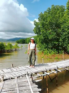 Traveller standing on a wooden jetty beside calm mangrove water during a hidden mangrove visit day trip in Labuan Bajo