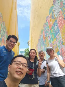 Group selfie in a painted alley of Katong-Joo Chiat during a Monopoly-style team-building walk in Singapore hidden gems.