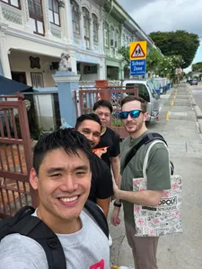 Group on a historic street in Singapore for a real-life Monopoly team game, smiling along the walkway  Singapore hidden gems